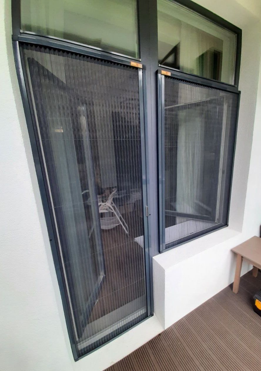A window and a balcony door, both fitted with pleated fly screens in anthracite frames
