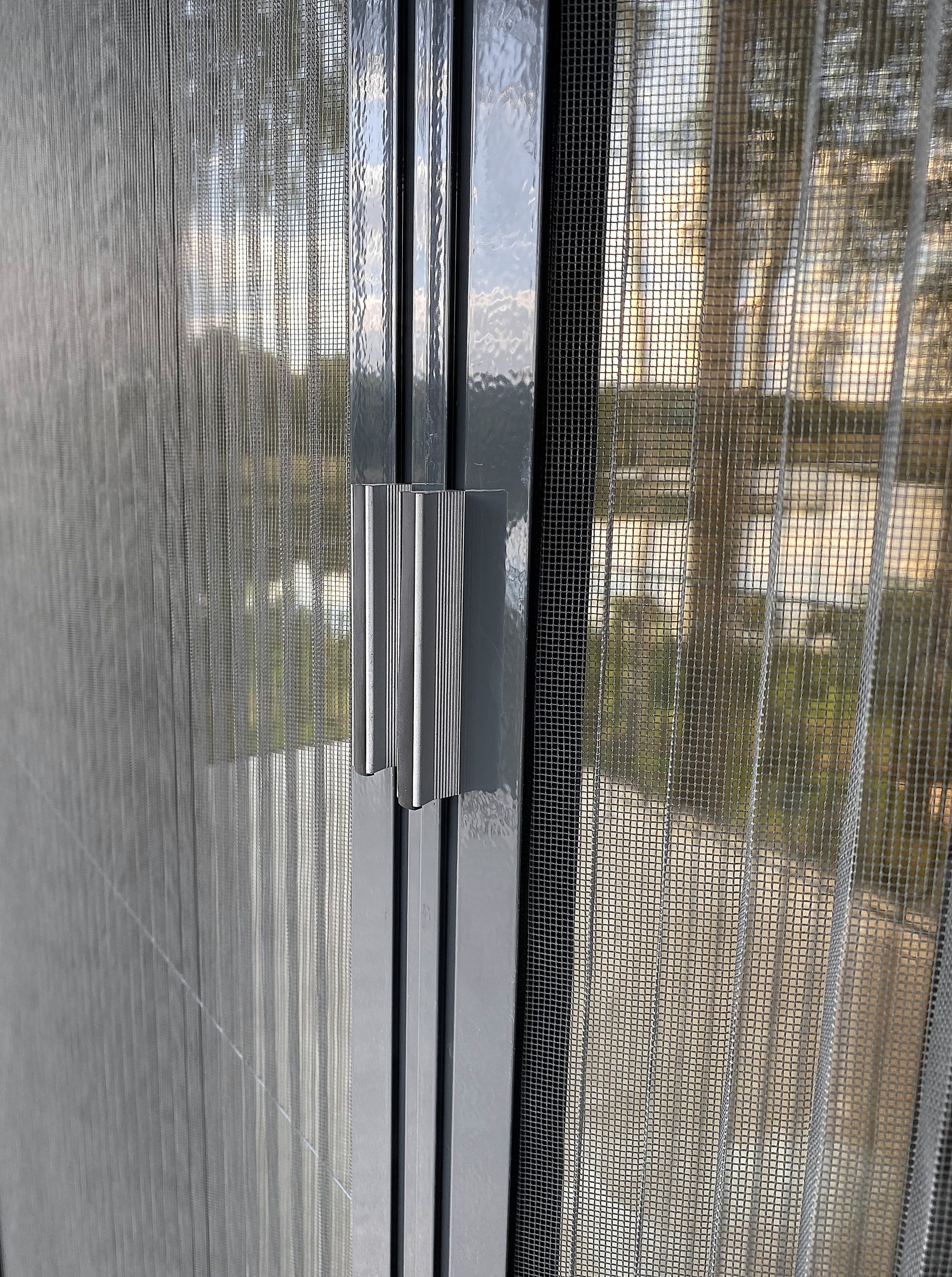 Close-up of a double pleated fly screen closing in the middle, with two slim aluminium handles and the fine pleated mesh