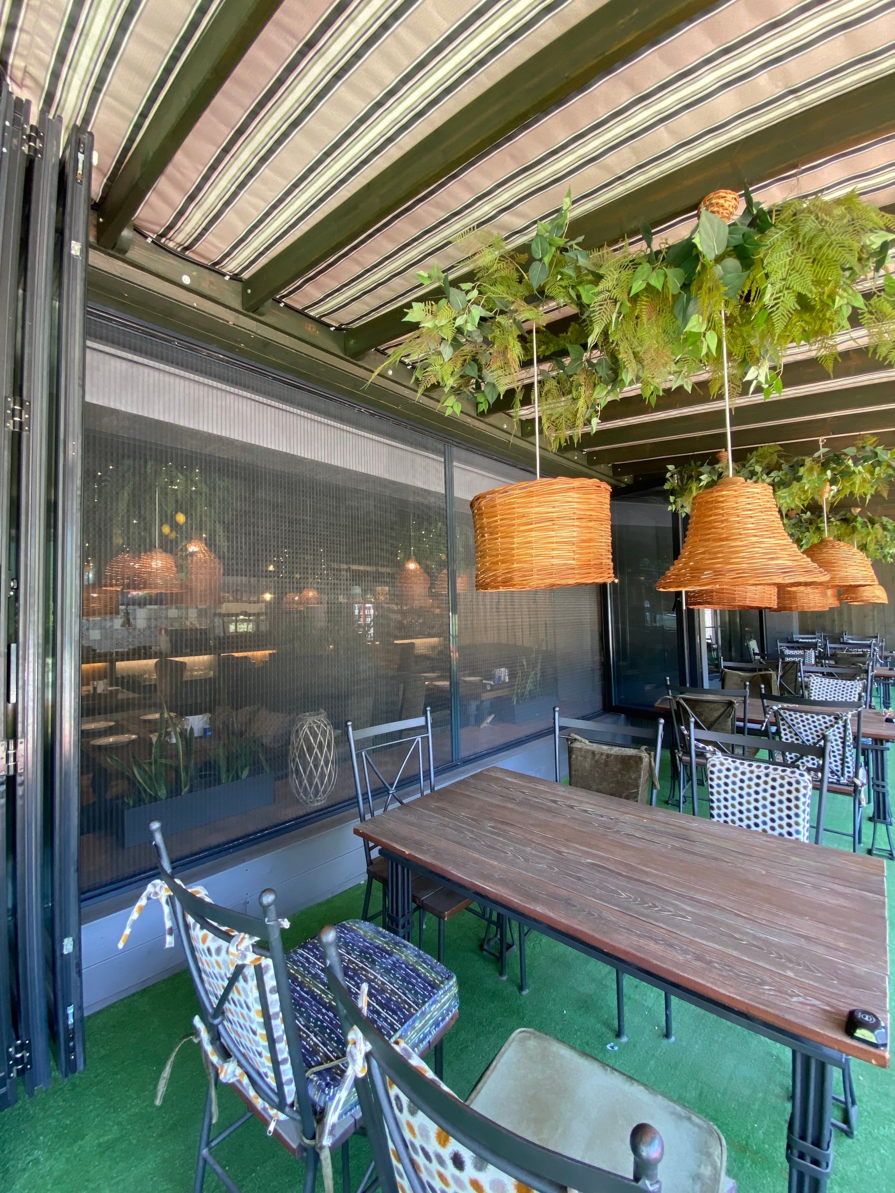 Terrace under a pergola with plissé fly screens along the large glazed openings