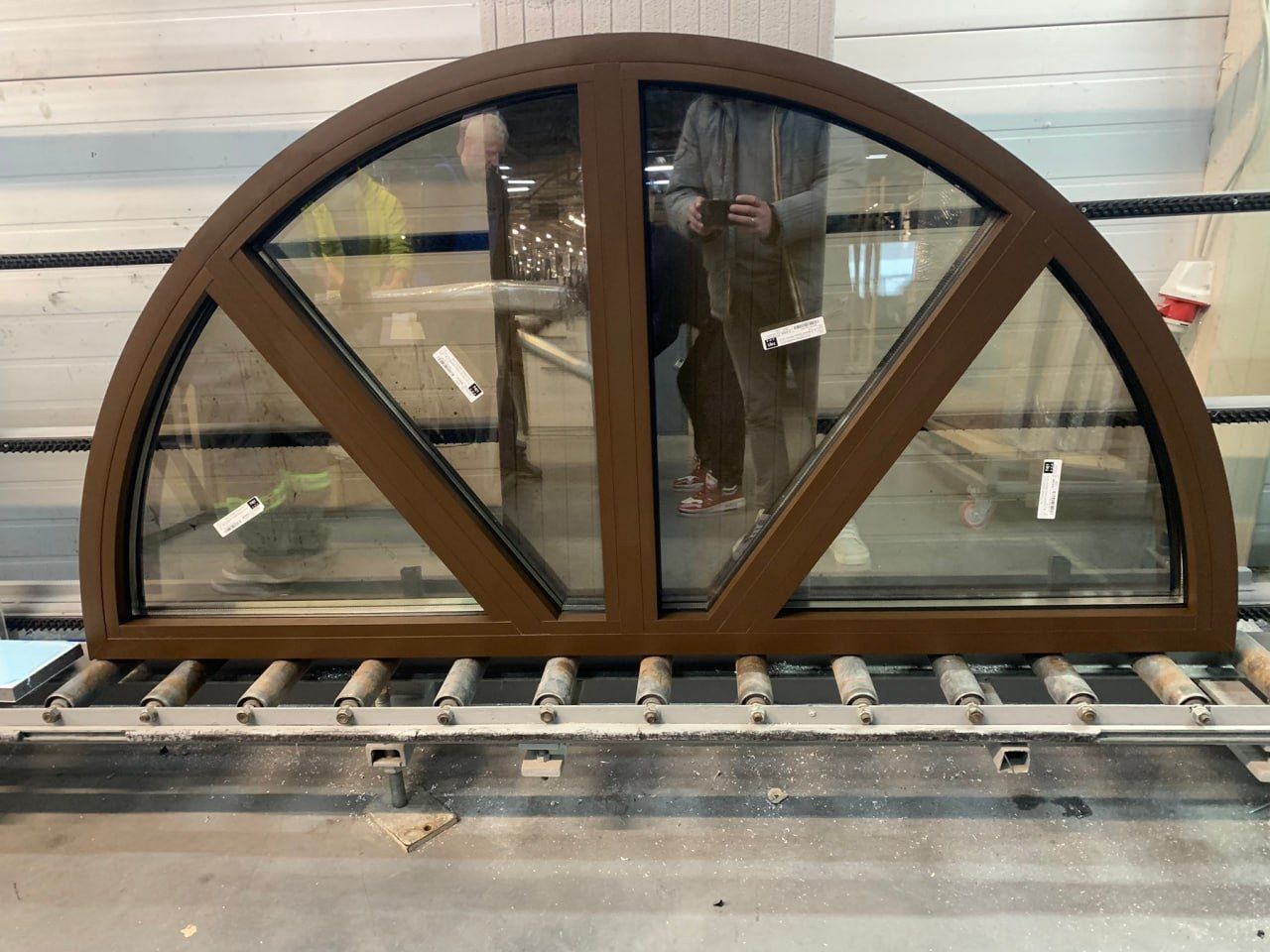Semicircular PVC window in a brown wood-effect finish, with three glazed sections, on the production line