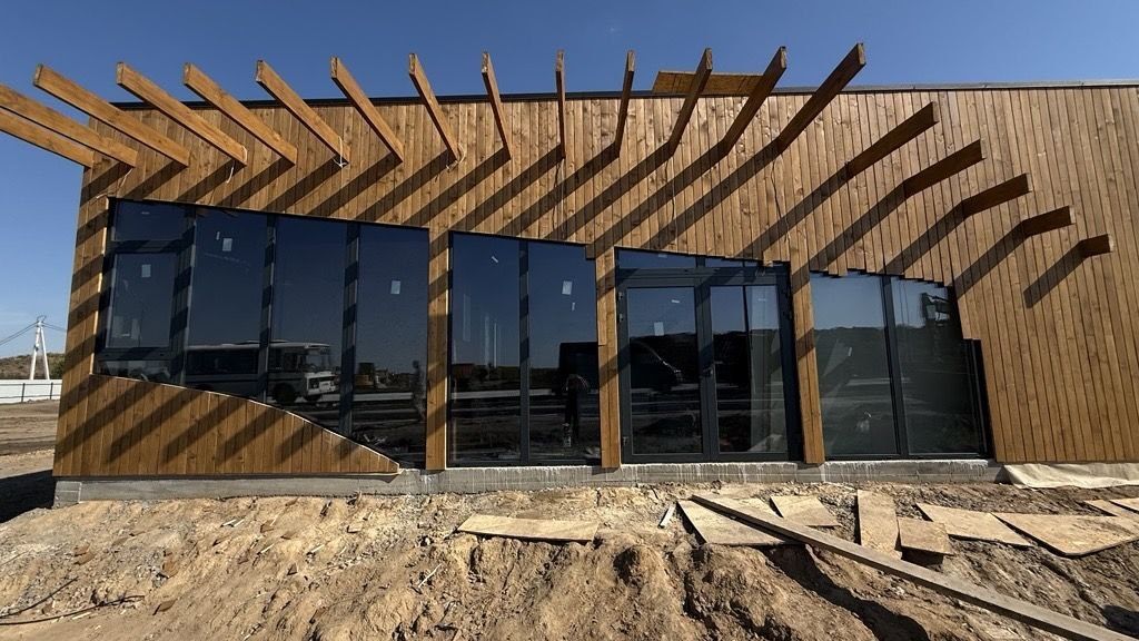 Edificio revestido de madera con grandes ventanas de perfil oscuro y una puerta doble acristalada